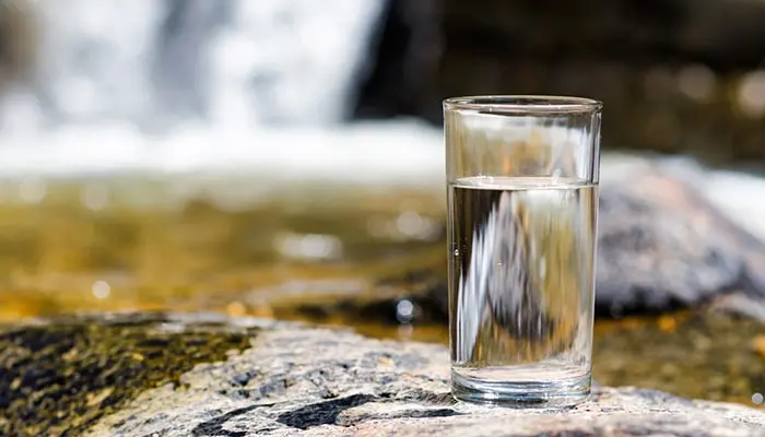 glass of water sitting near waterfall